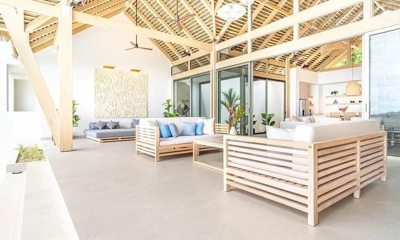 Casa Frenchie & Guest House · 17. An open-plan living area with high vaulted wooden ceilings and exposed beams provides ample natural light and multiple seating areas, connecting to adjacent spaces through large glass doors.