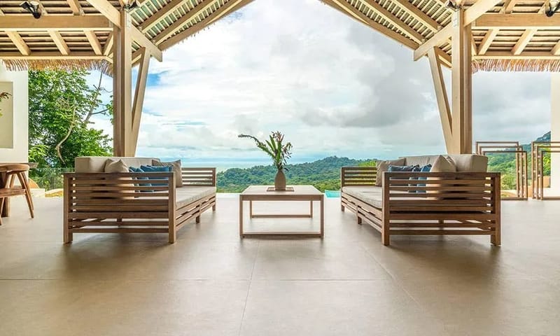 Casa Frenchie & Guest House · 21. An expansive, open-air terrace with a high vaulted wooden ceiling provides comfortable lounge seating and unobstructed panoramic views of the jungle and distant ocean.