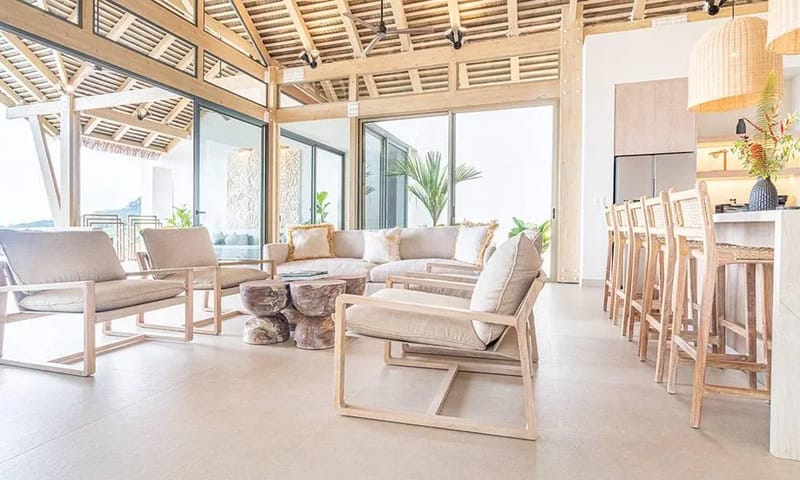 Casa Frenchie & Guest House · 24. This expansive open-plan living area features high vaulted wooden ceilings and a seamless flow to an integrated kitchen bar, all illuminated by wide glass doors offering connection to the outdoor landscape.