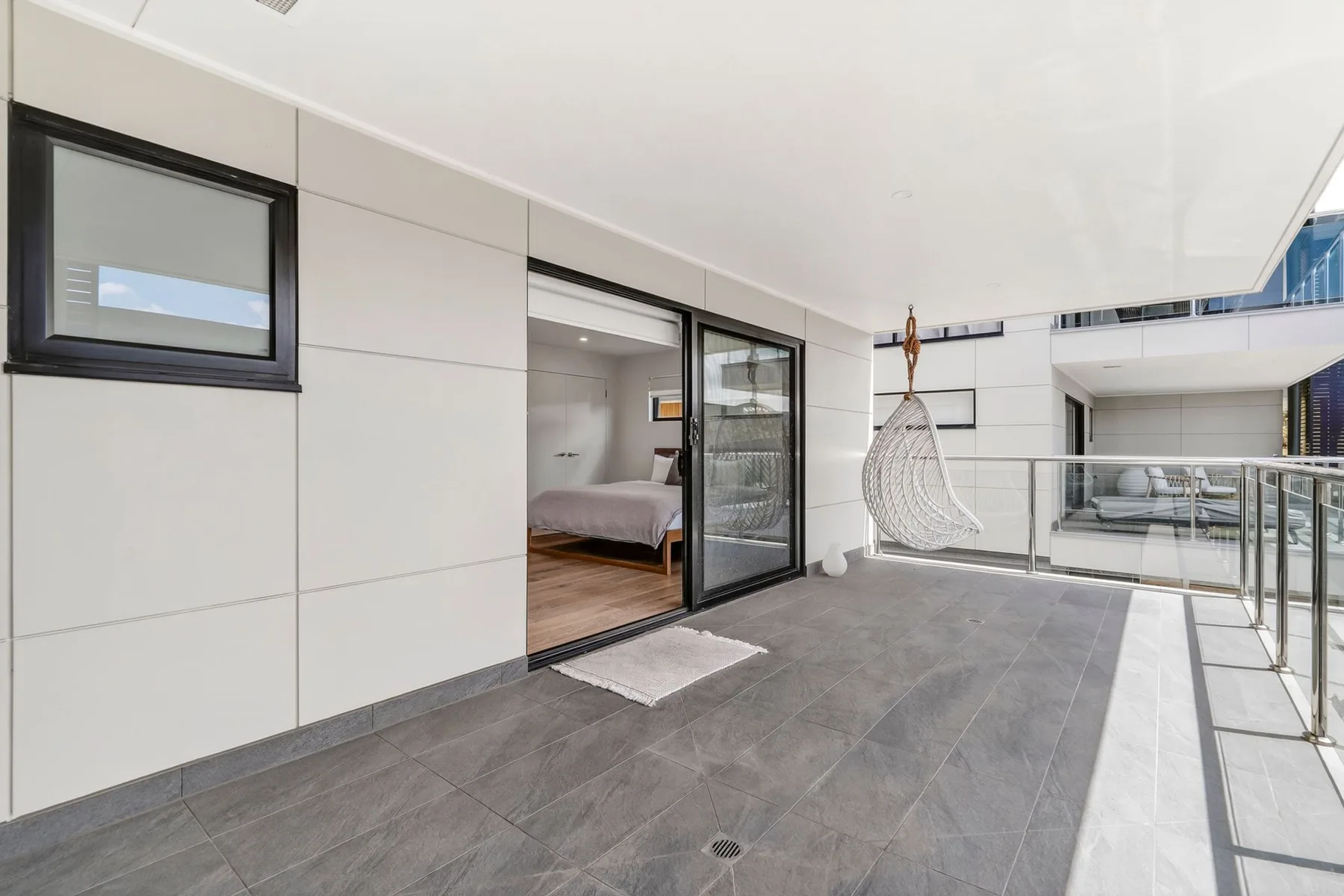 Una terraza exterior con suelo de baldosas y puertas correderas que dan a un dormitorio.