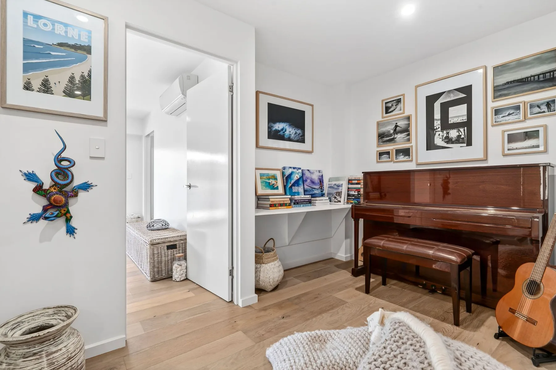Una sala de música con piano, guitarra y cuadros en las paredes.