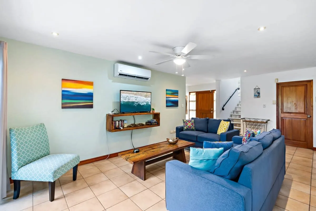 A living room with blue seating, a wooden coffee table, and colorful wall art.