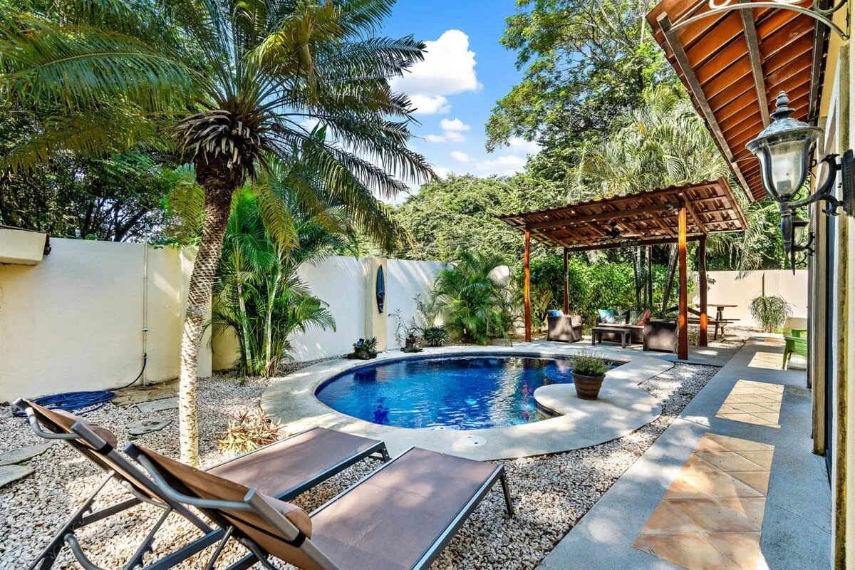 A courtyard pool beside lounge seating and a shaded outdoor dining area.
