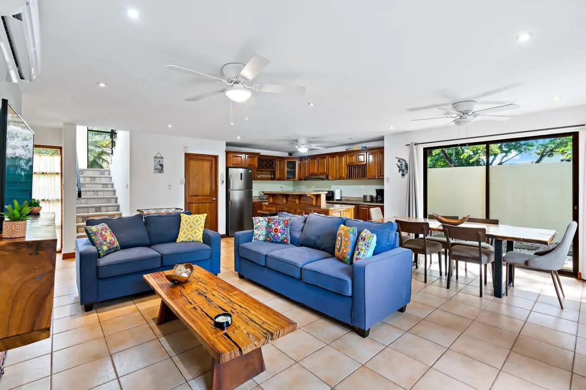 An open-plan living and dining area with blue seating and a wooden kitchen.