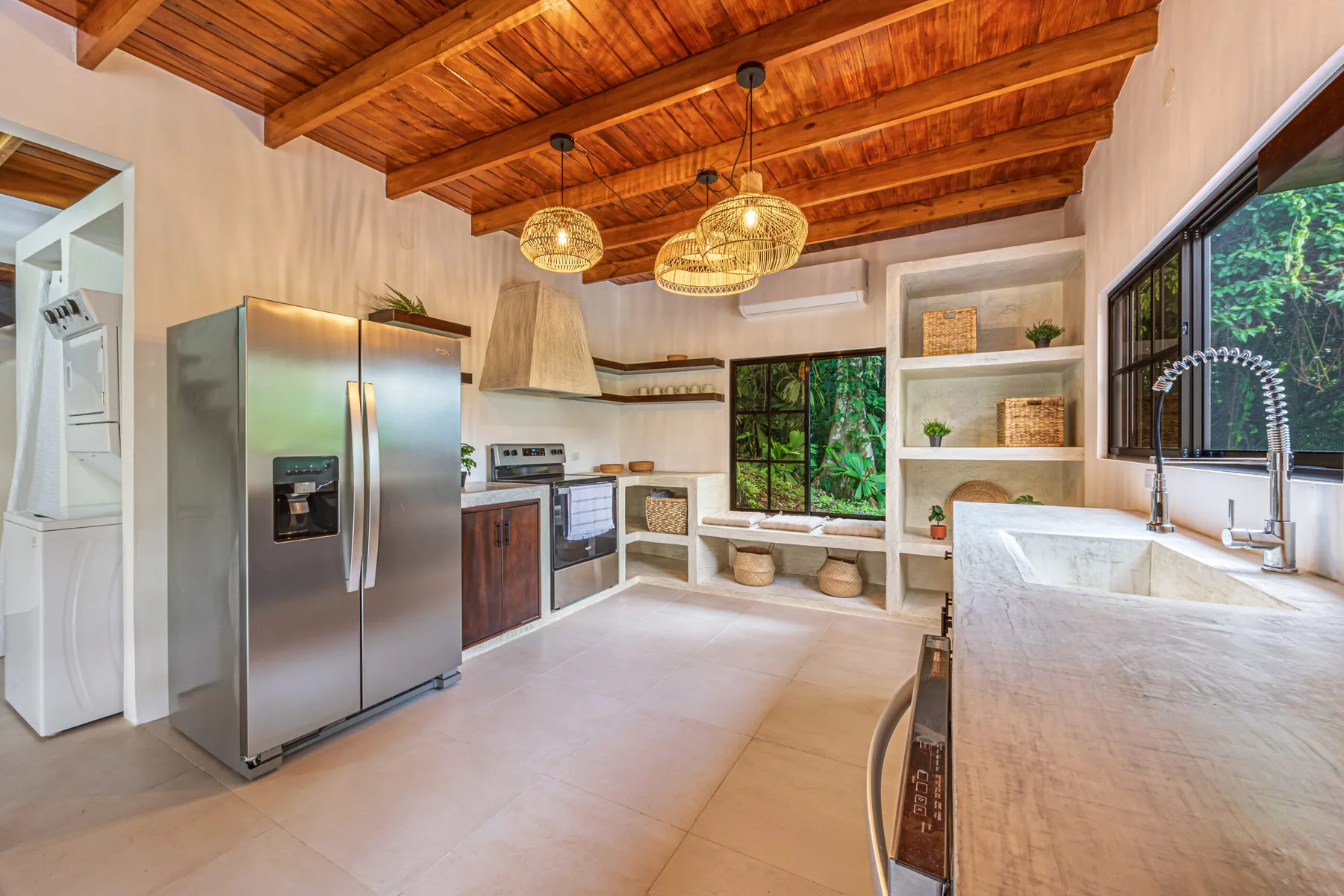 A bright kitchen with wooden ceiling beams, stainless steel appliances, and a large island.