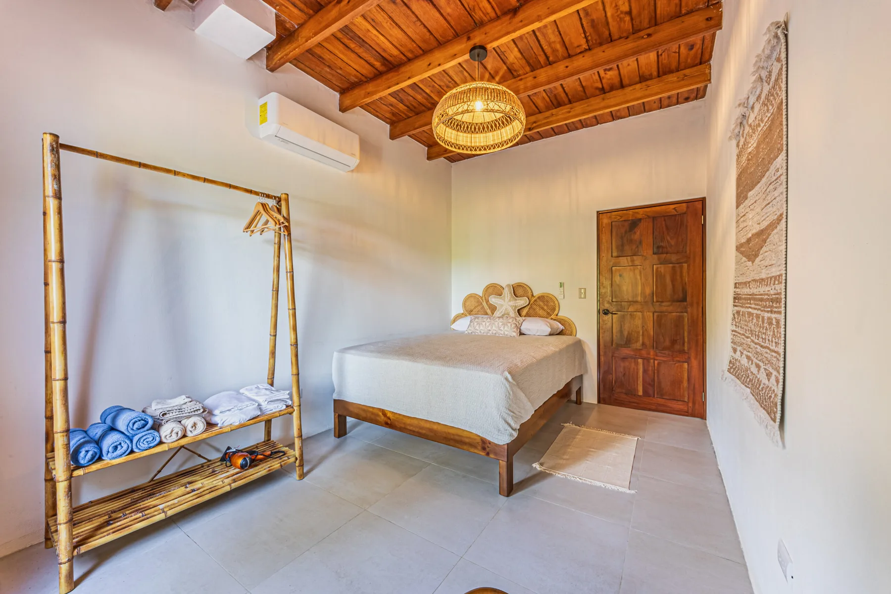 A bedroom with a bed beneath a wood-paneled ceiling and a bamboo towel rack.