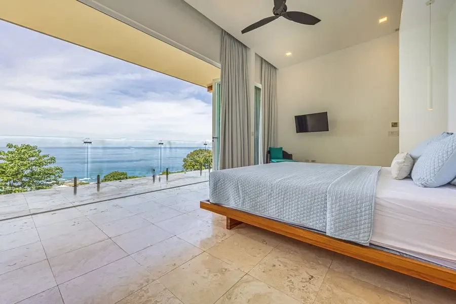 A bedroom opens onto a terrace with a view of the sea.