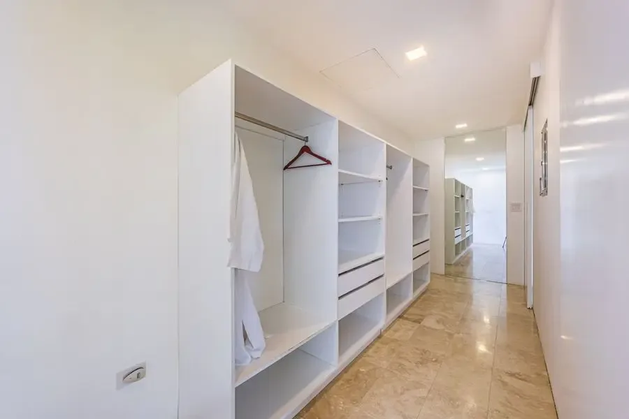 A bright hallway with open built-in shelving and hanging clothes.