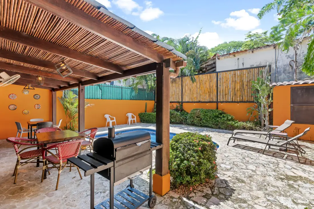 An outdoor patio with a covered seating area and a barbecue grill.