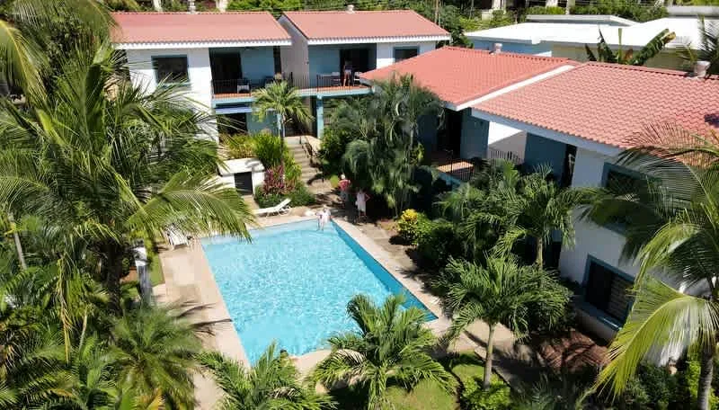 Aerial view of a swimming pool beside low-rise buildings with red roofs.