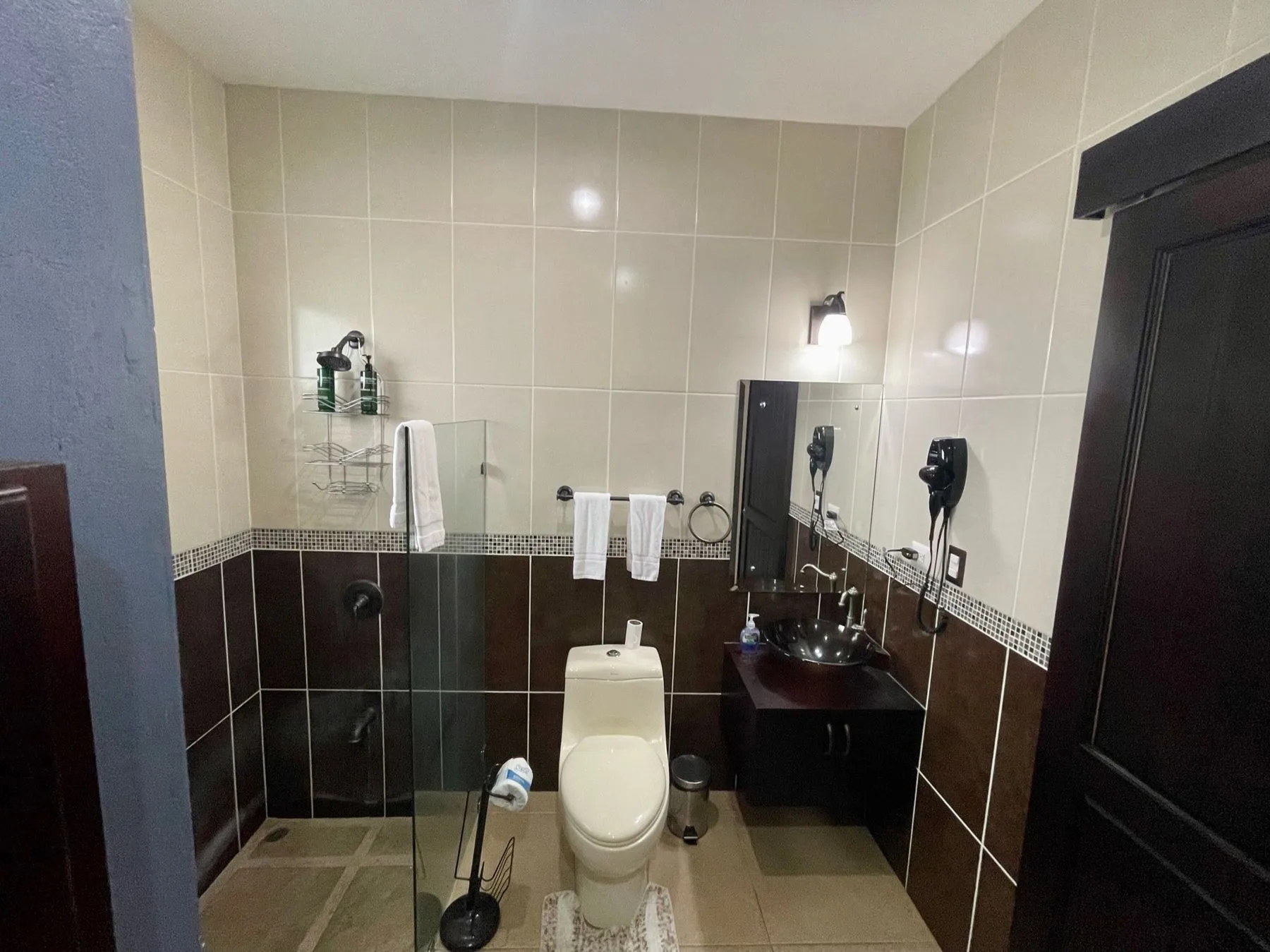 A tiled bathroom with a shower area, toilet, and sink.