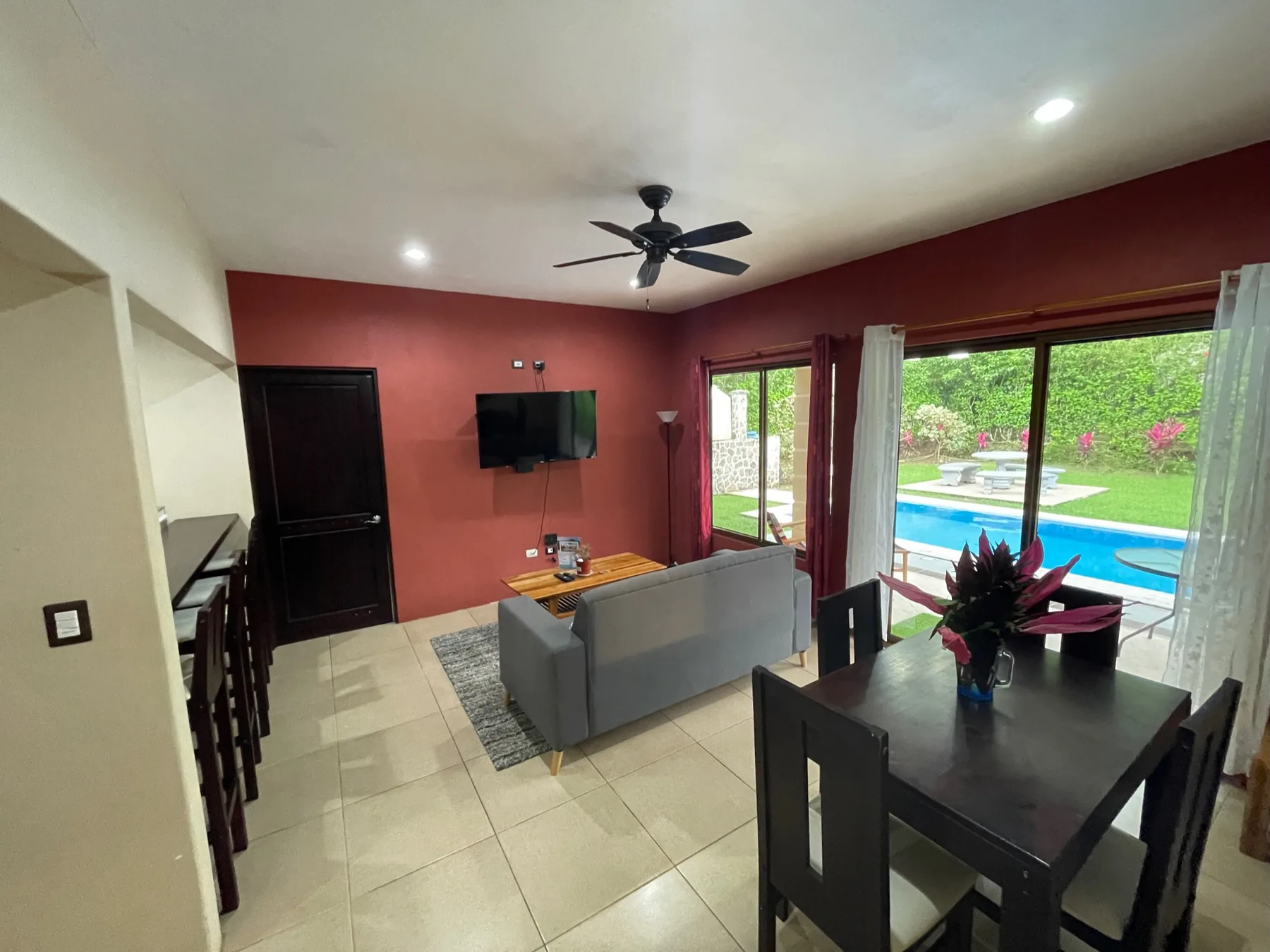 A living and dining area opens onto a patio with a swimming pool.