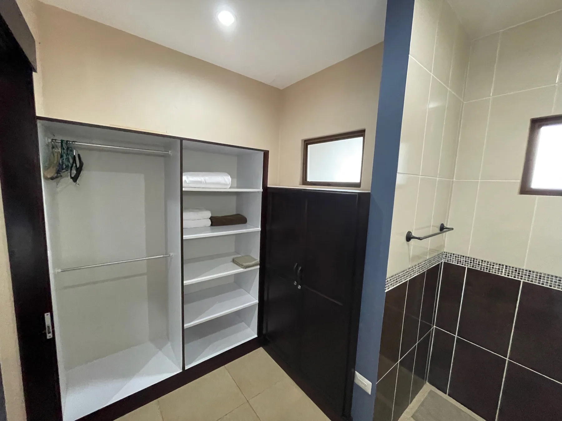 A bathroom with open storage shelves and a tiled shower area.