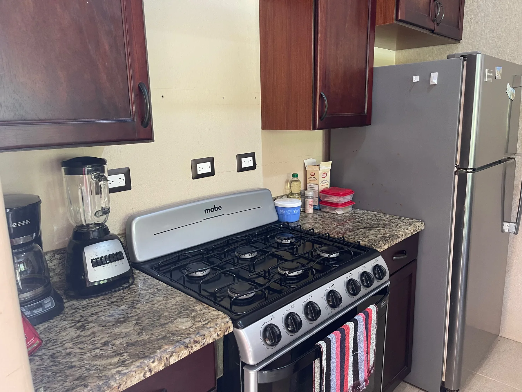 A kitchen with a gas stove, countertop, and refrigerator.