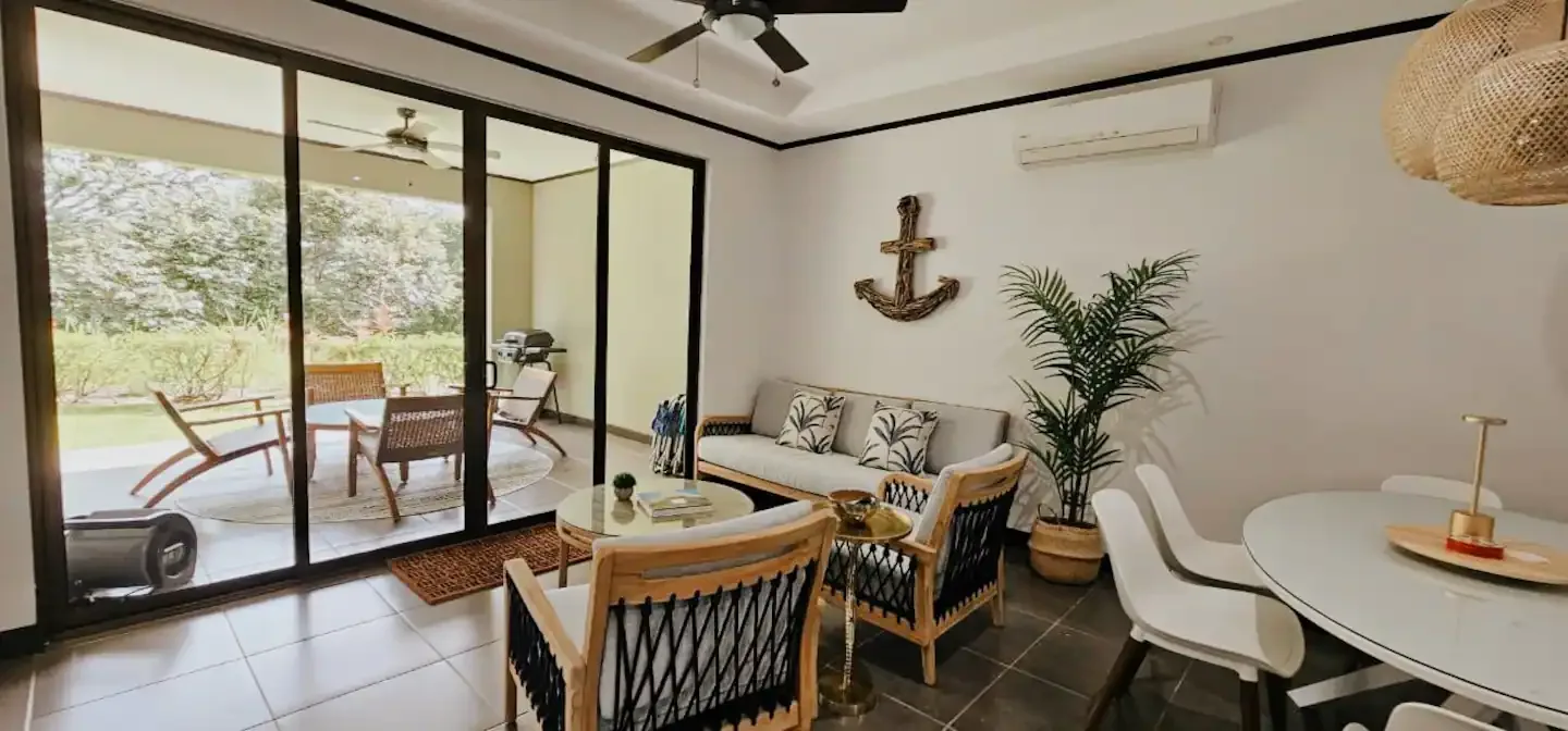 A bright dining and sitting area opens onto a patio through large glass doors.
