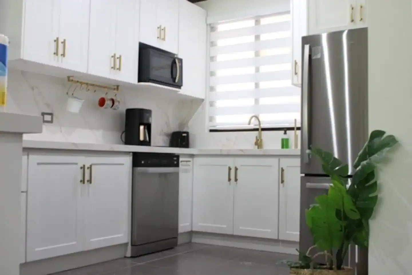 A bright kitchen with white cabinets, stainless steel appliances, and a window above the sink.