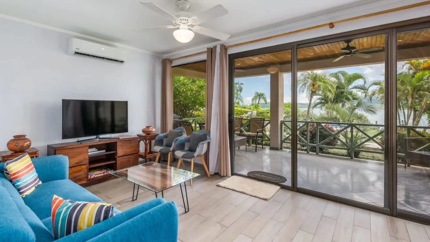 A living room with seating and a television beside large glass doors.