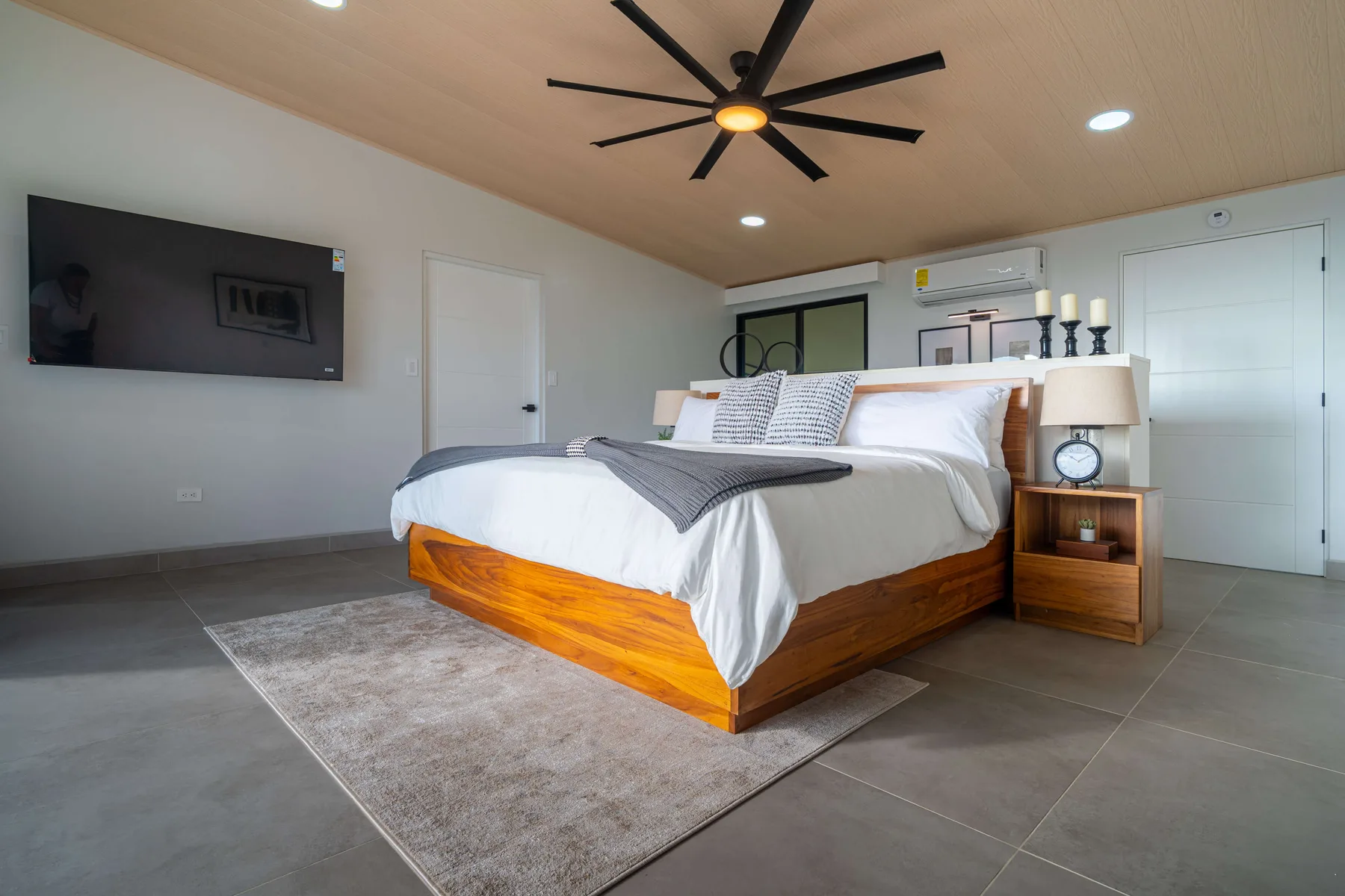 Un dormitorio con una cama bien tendida y un televisor montado en la pared.