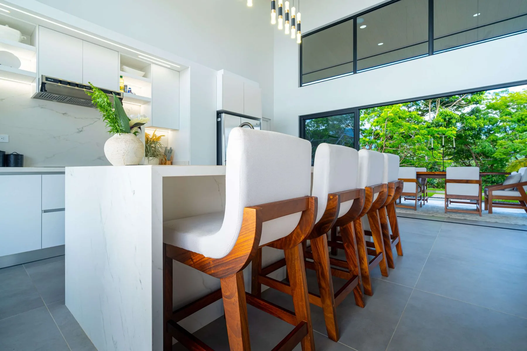 Una cocina y comedor modernos y luminosos, con asientos junto a grandes ventanales.