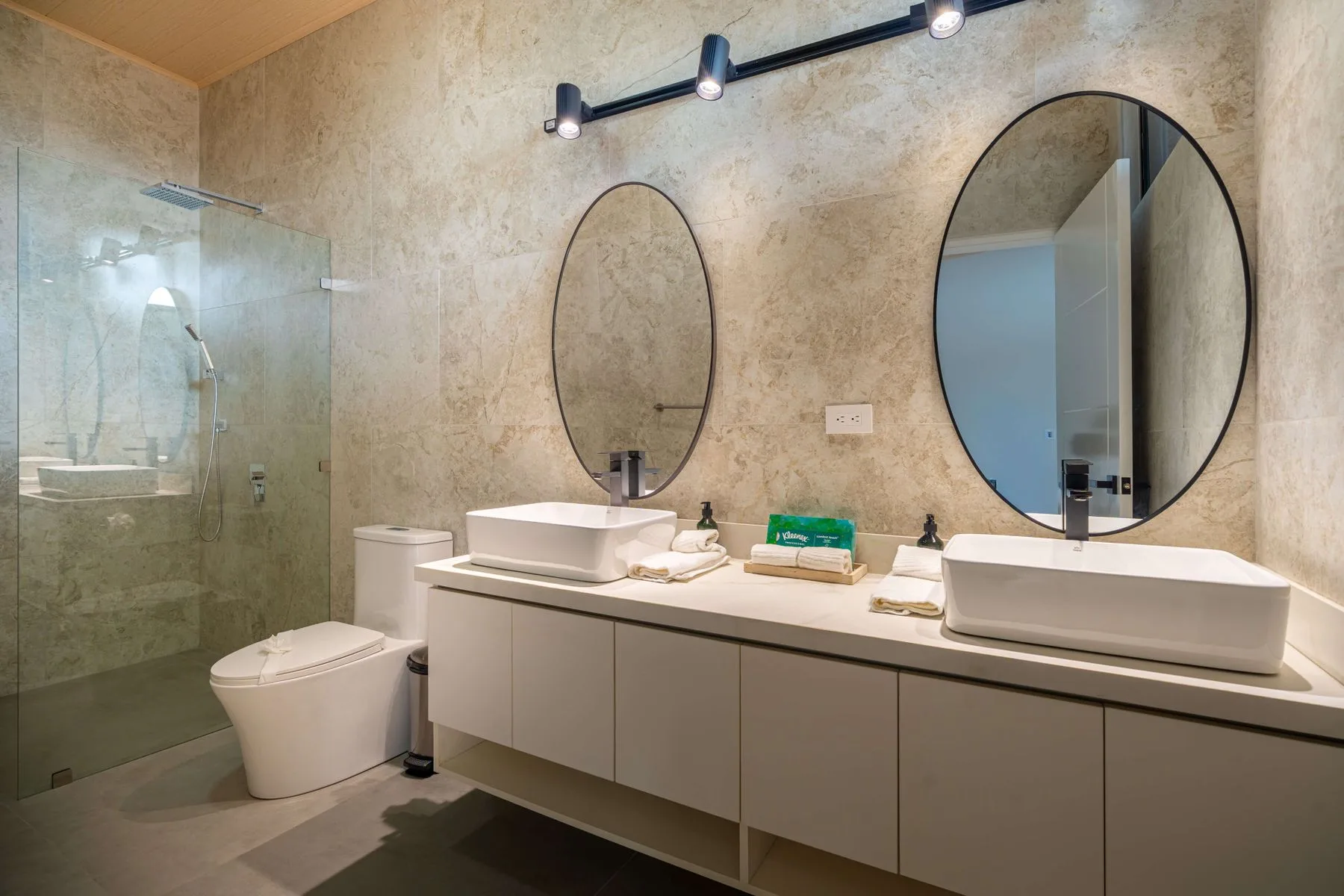 Un baño moderno con lavabo doble, espejos y una ducha de vidrio.