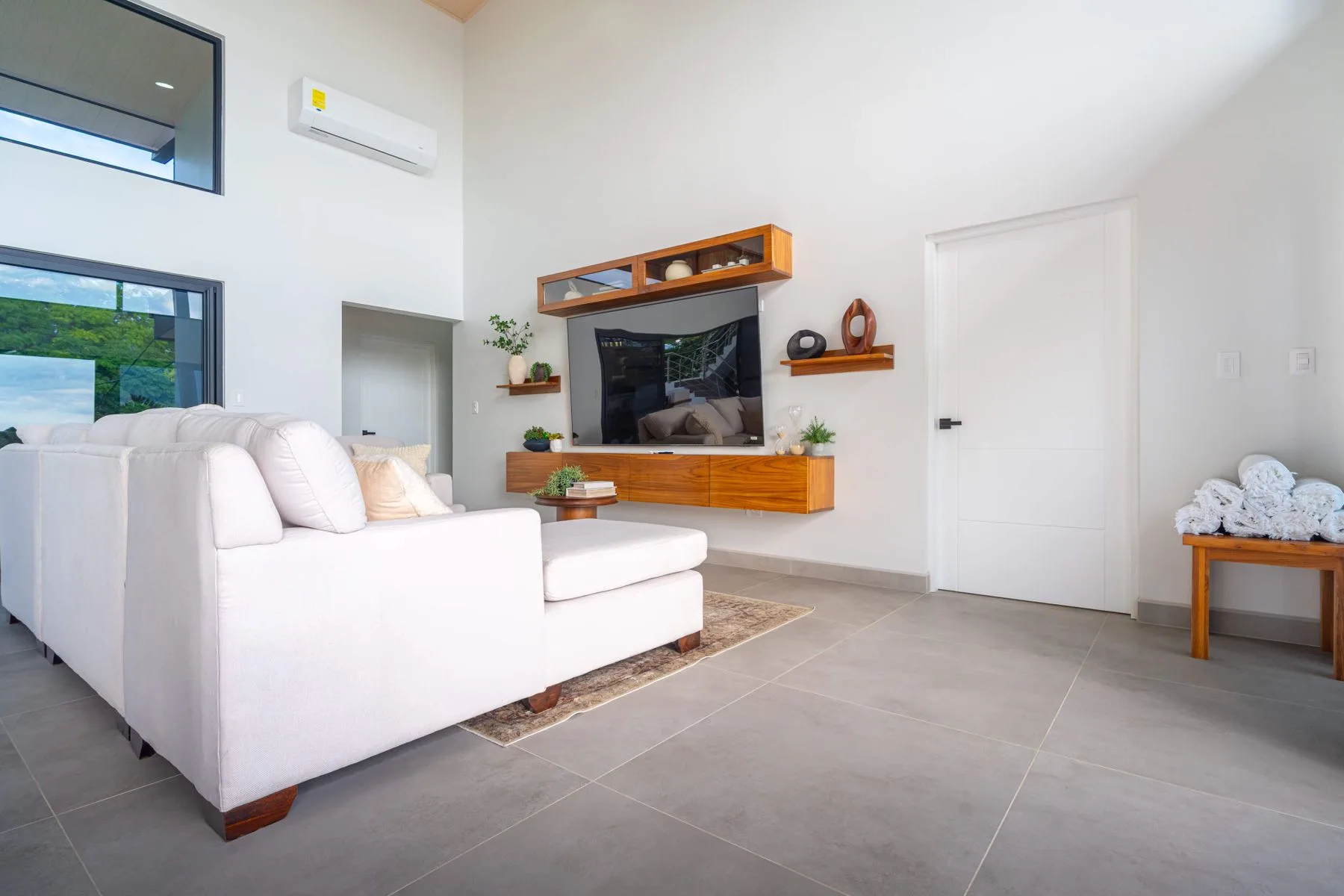 Una sala luminosa con asientos blancos y un televisor montado en la pared.