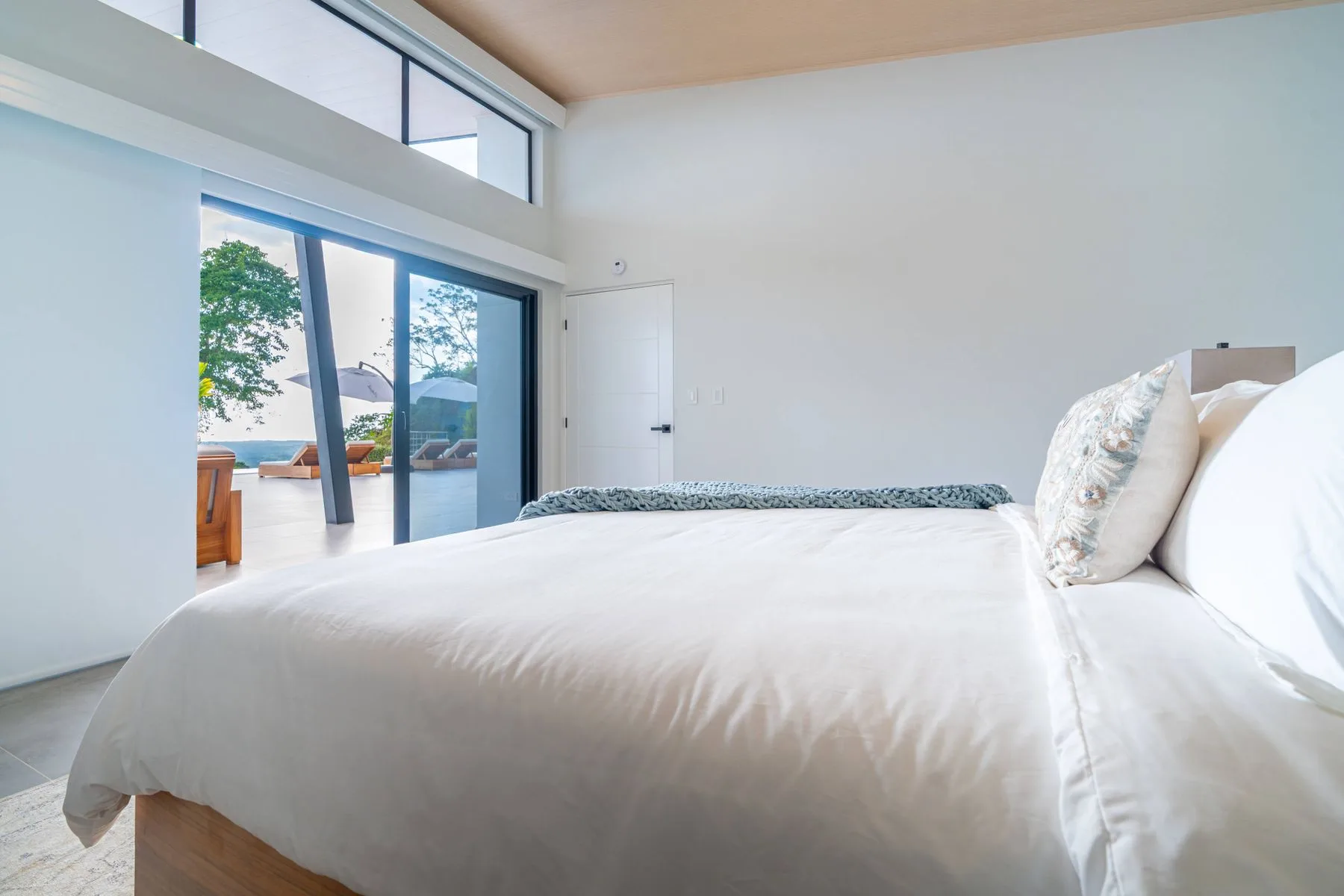 Un dormitorio luminoso con una cama junto a grandes puertas corredizas de vidrio.