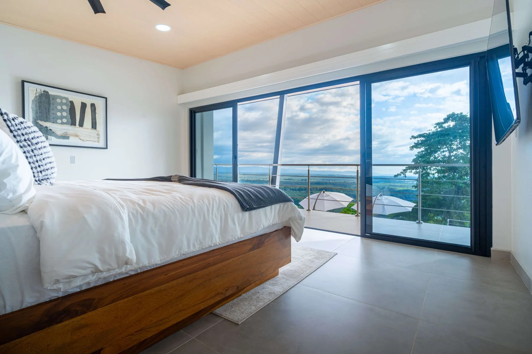 Un dormitorio con una cama junto a amplias puertas de vidrio con vistas al agua.