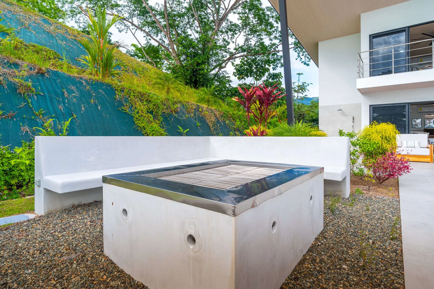 Una zona de estar al aire libre rodea una fuente cuadrada junto a un edificio moderno.