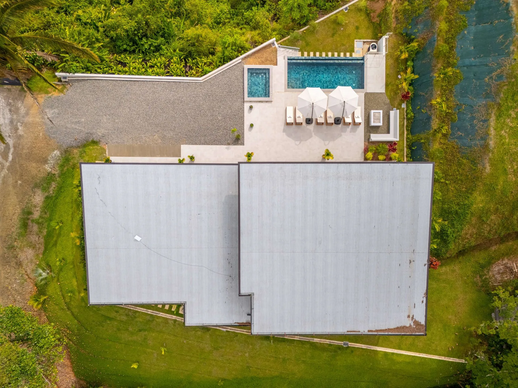 Una vista aérea muestra una piscina y un patio junto a un gran techo.