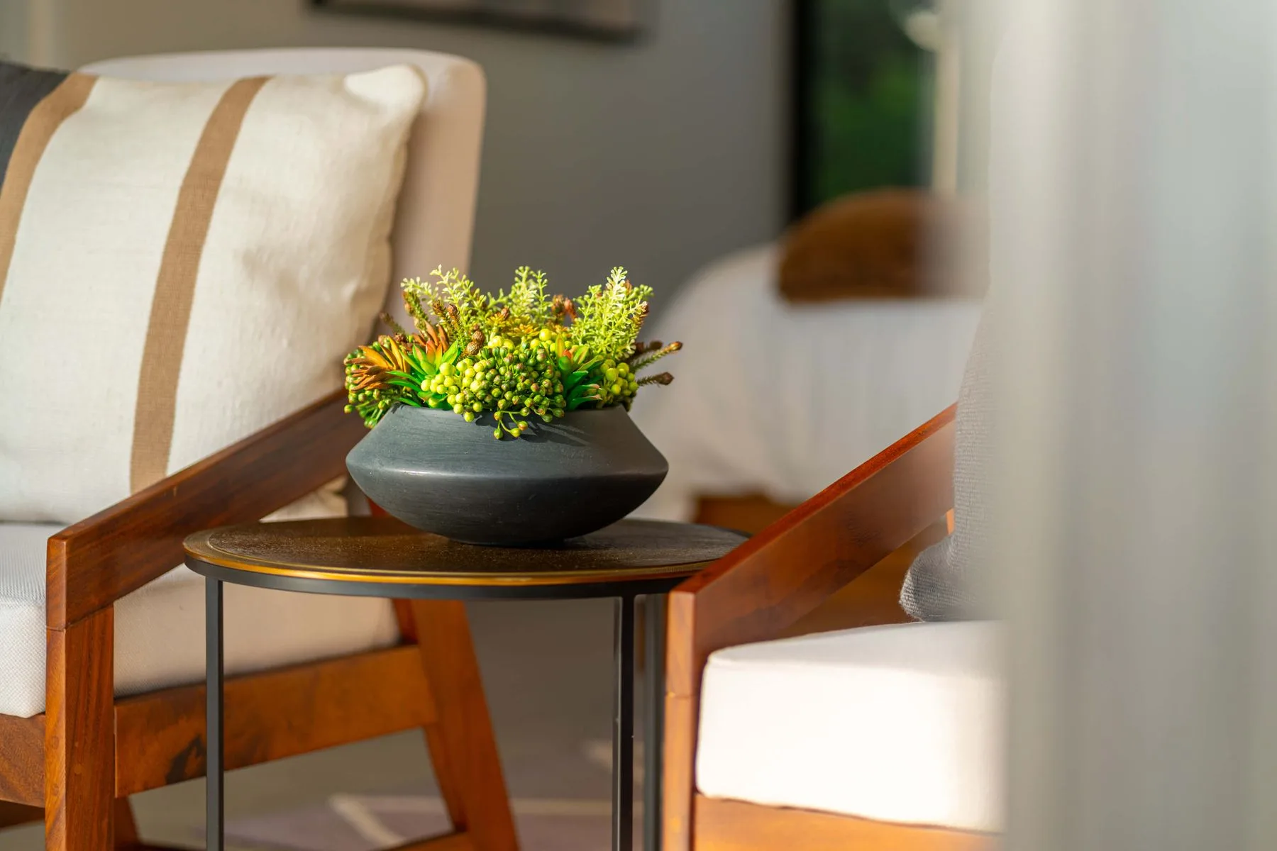 Una mesa pequeña con un arreglo floral está entre asientos tapizados.