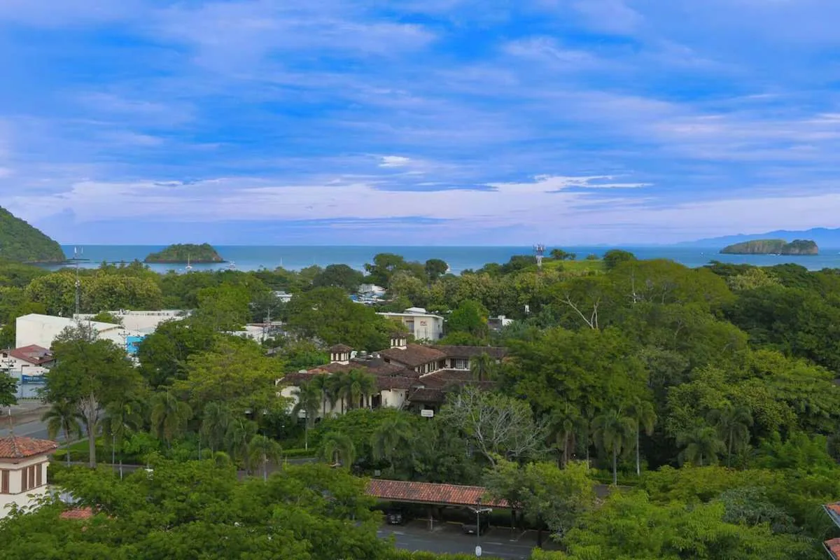Aerial view of a green coastal landscape with buildings, ocean, and islands.