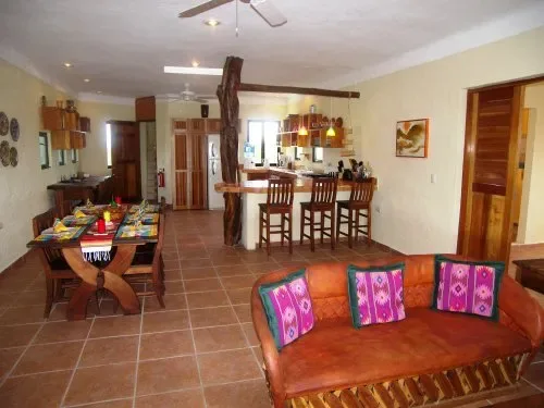Un espacio abierto de comedor y sala con mesa, barra de cocina y asientos.