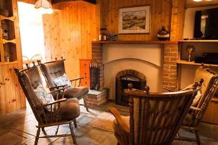 Una sala con paneles de madera y sillones alrededor de una chimenea de ladrillo.
