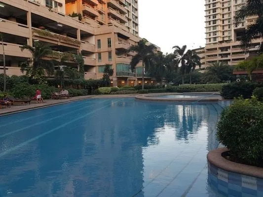 Una piscina al aire libre está rodeada de jardines y edificios residenciales altos.