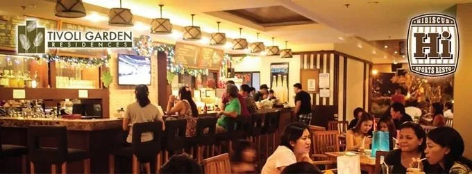 Un comedor de restaurante con una barra larga y clientes sentados a las mesas.