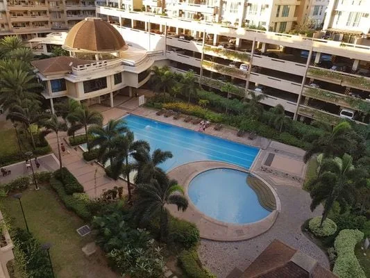 Un patio ajardinado con una piscina y otra piscina circular conectada.