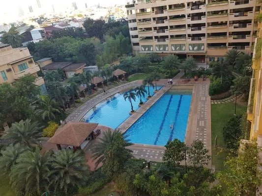 Una piscina al aire libre está rodeada de palmeras y edificios.