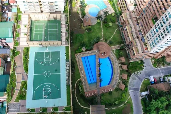 Una vista aérea muestra canchas deportivas al aire libre, piscinas y jardines.