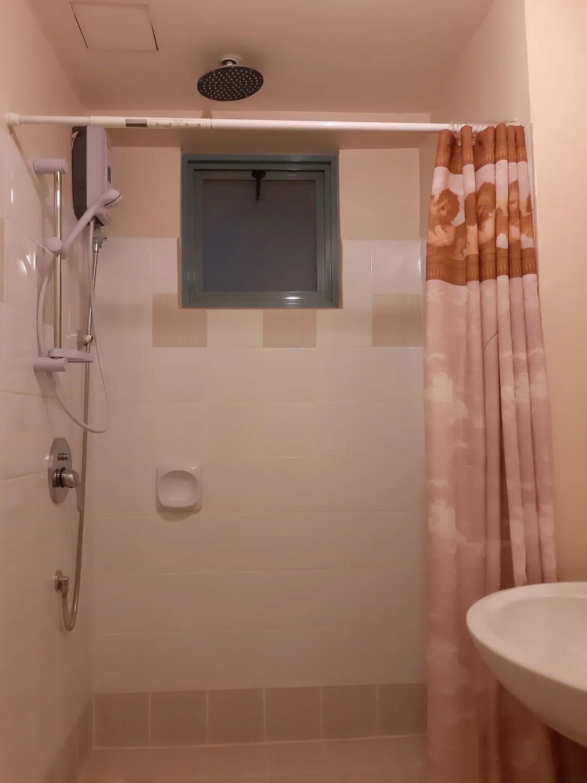 Baño alicatado con ducha, ventana y lavabo.