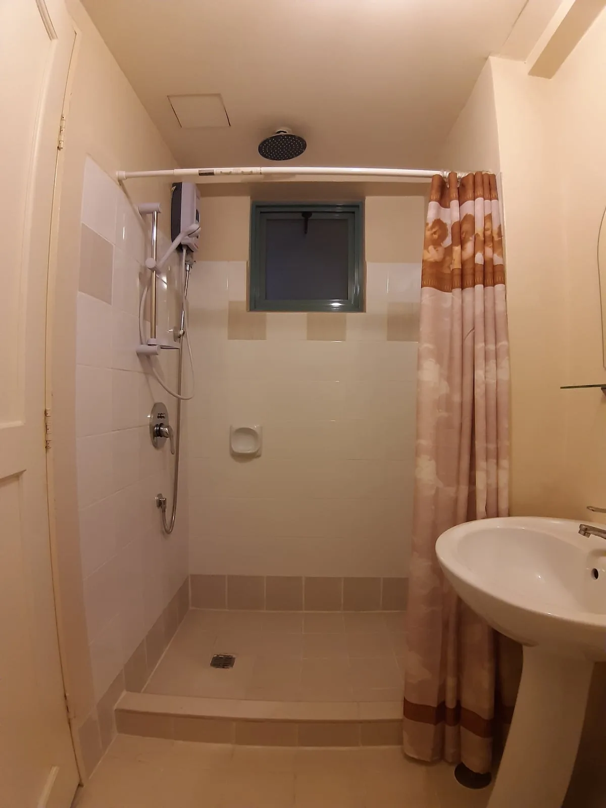 Un baño con ducha, cortina estampada y lavabo con pedestal.