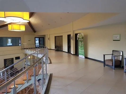 Un amplio vestíbulo interior tiene una barandilla curva de metal y asientos junto a la pared.