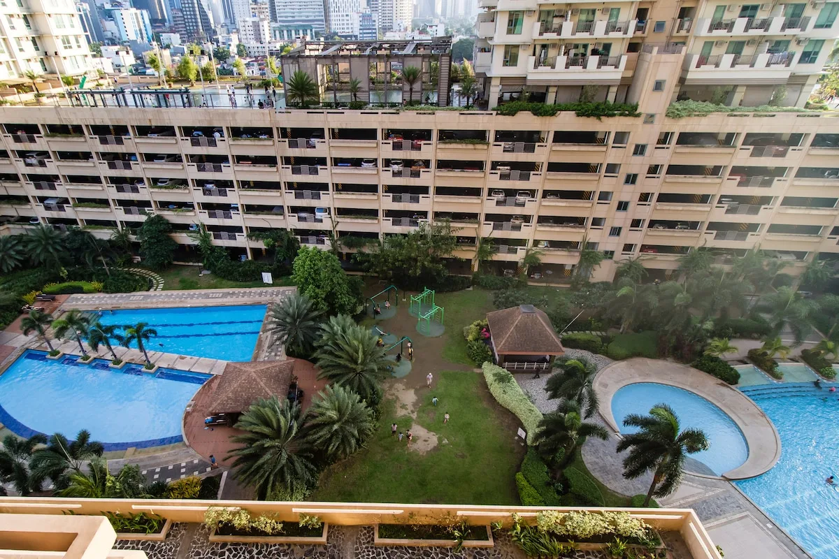 Vista aérea de un patio exterior con piscinas y zonas ajardinadas.