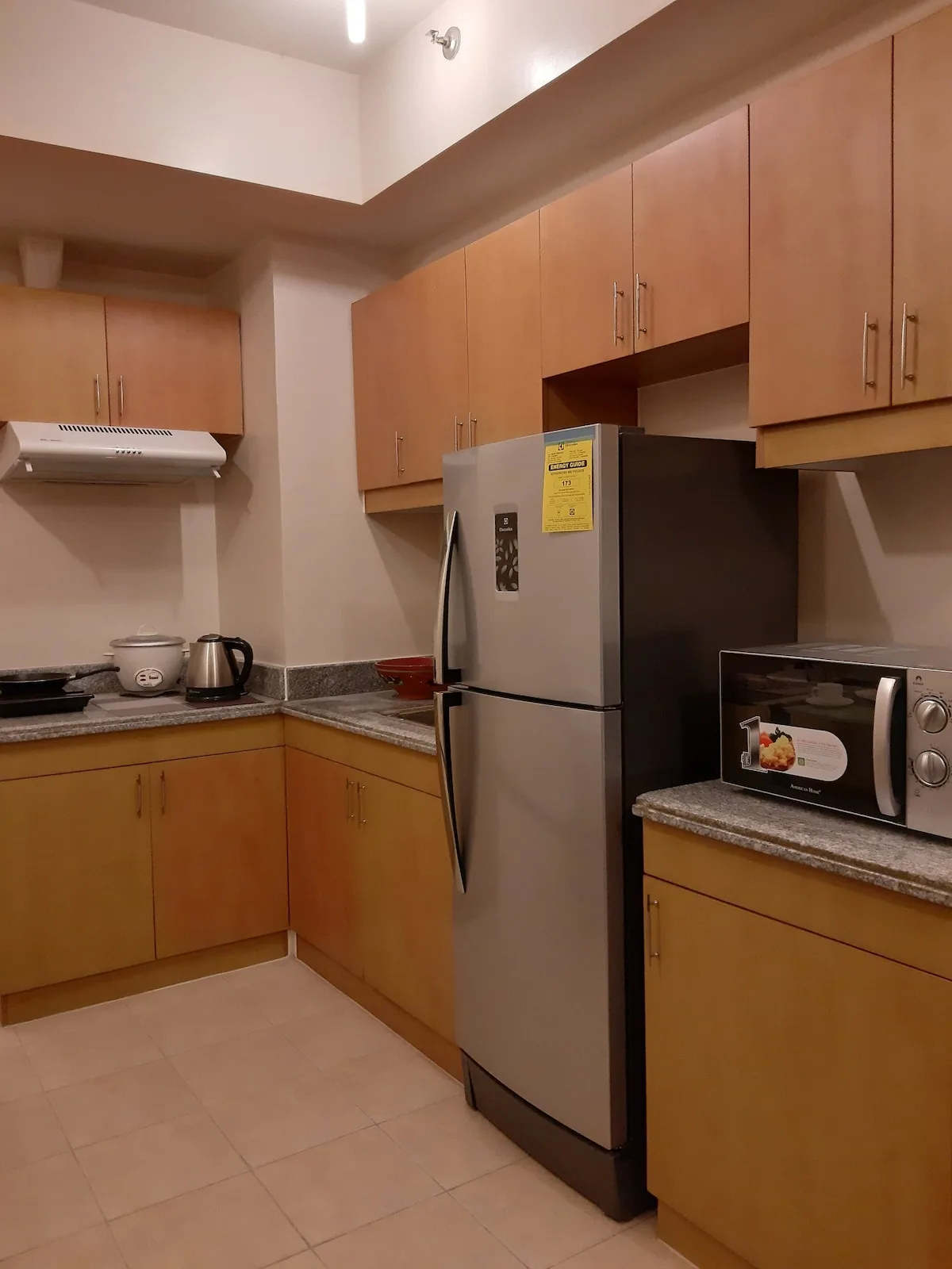 Una cocina con gabinetes de madera, un refrigerador y un microondas.