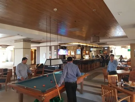 Un bar y comedor de restaurante con una mesa de billar en primer plano.