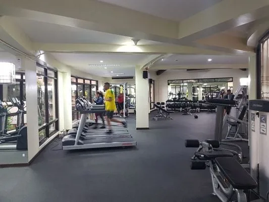 Un gimnasio con cintas de correr, máquinas de ejercicio y una zona de entrenamiento con espejos.