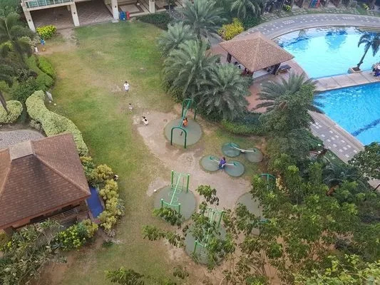 Vista aérea de un patio ajardinado con piscina y zona de juegos.