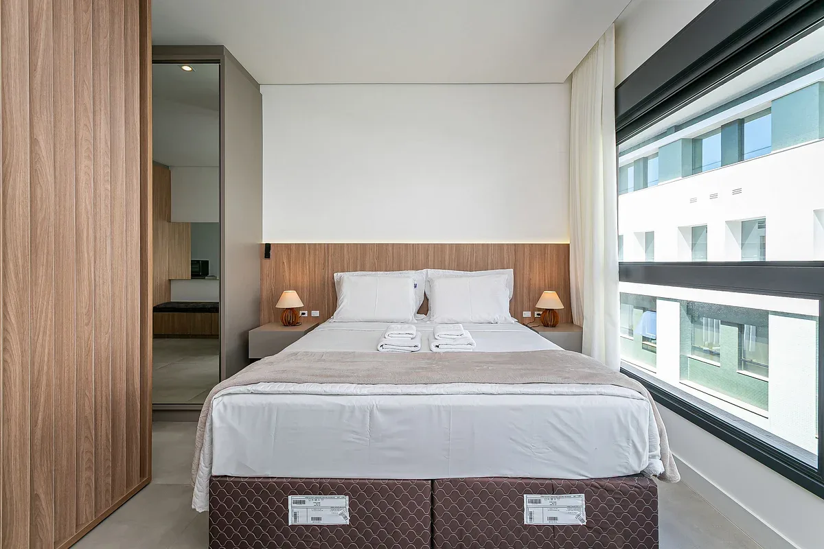 A bedroom with a neatly made bed and a large window.