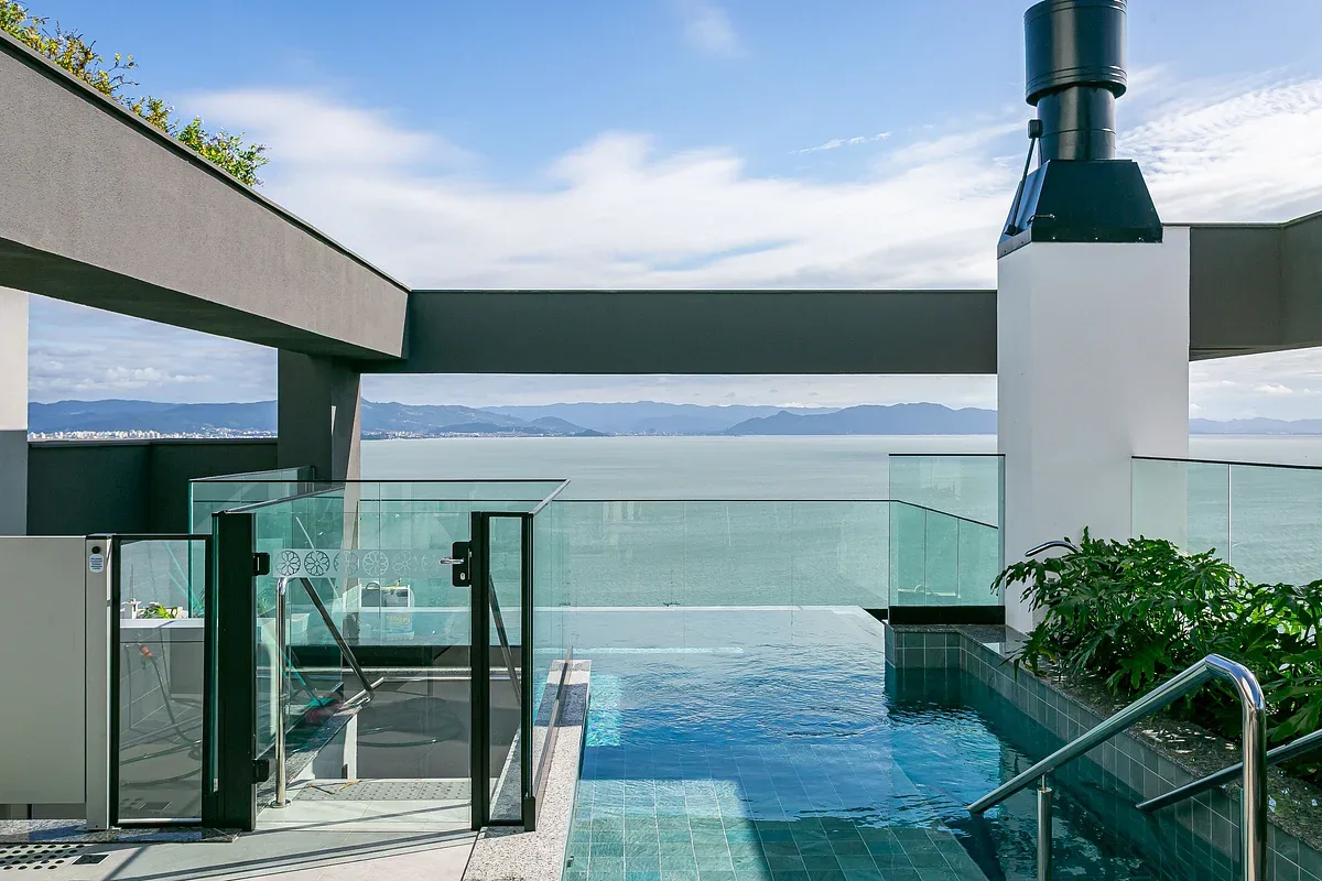 A rooftop swimming pool overlooks the water and distant mountains.