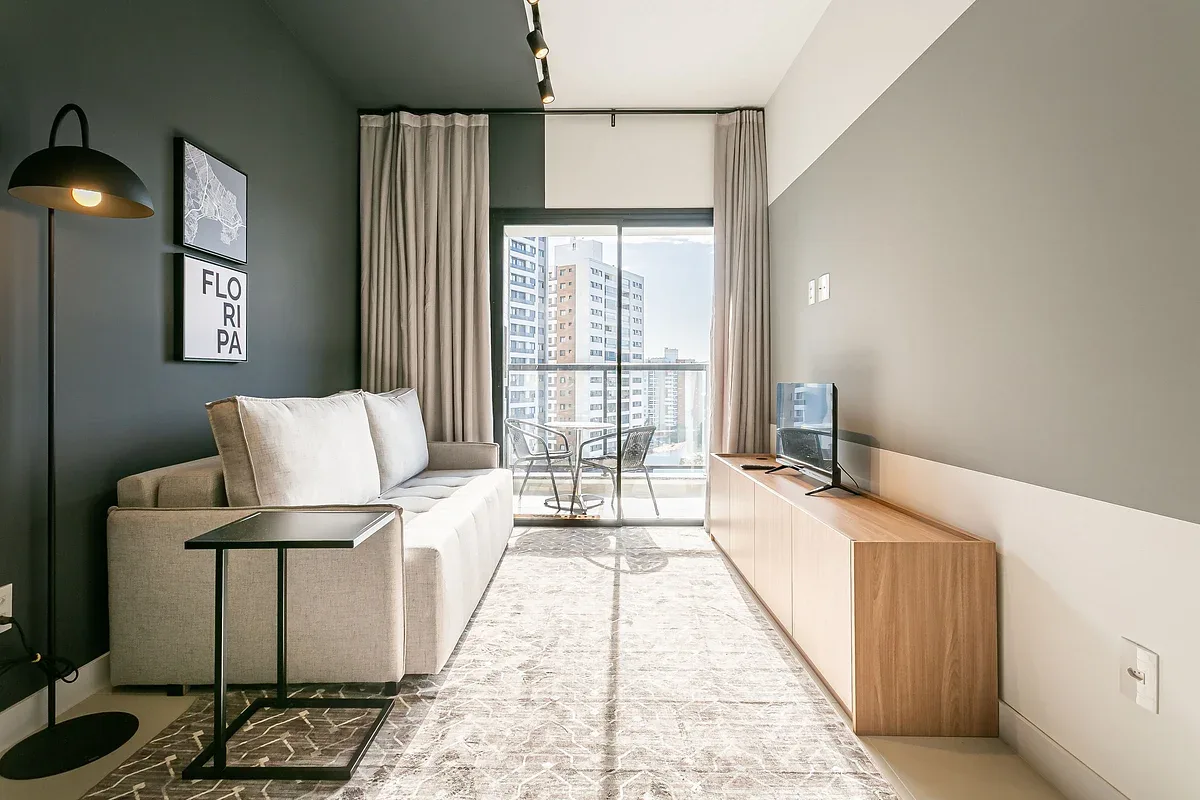 A living room with a sofa, television, and glass doors opening onto a balcony.
