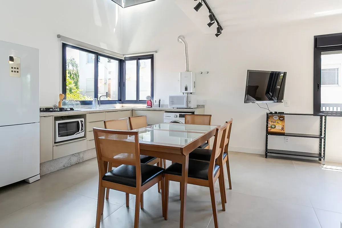 A bright kitchen and dining area with a glass-topped table and large windows.